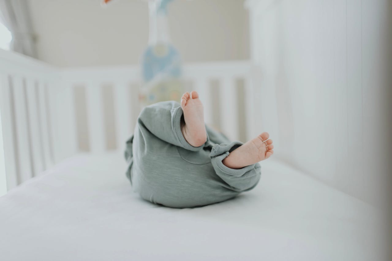 Cute baby feet in pajamas on a soft white crib. Perfect for childrens room decor.